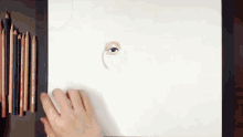 a person is drawing a woman 's eye on a piece of paper with colored pencils .