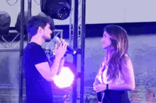 a man singing into a microphone next to a woman looking at him