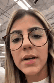 a woman wearing glasses looks at the camera with a serious look on her face