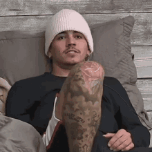 a man with a tattoo on his leg wearing a pink beanie