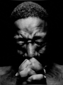 a man is praying with his hands folded in front of his face