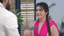 a woman in a pink dress is holding a wallet and talking to a man .
