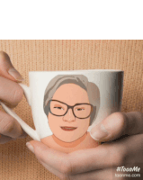 a person is holding a coffee cup with a cartoon of a woman 's face on it
