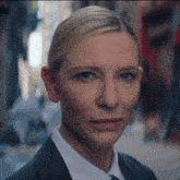 a woman in a suit and tie looks at the camera with a serious look on her face