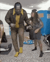 a man in a suit is dancing in front of a portable toilet that says viggle.ai
