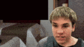 a young man sitting in front of a table with a table cloth on it