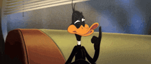 a cartoon duck is sitting on a couch with his finger on his lips