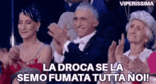 a group of people are sitting in a row clapping their hands in a crowd .