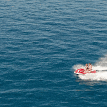 two people are riding a red and white jet ski in the ocean