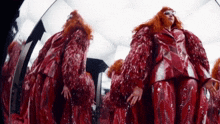 a woman with red hair is standing in front of a mirror wearing a red coat