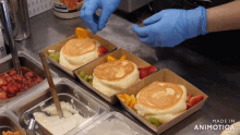 a person wearing blue gloves is preparing pancakes with fruit toppings