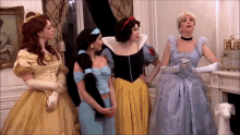 a group of women dressed as princesses are standing in a room