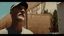 a man with a beard wearing a baseball cap is looking up .