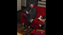 a man sitting on a red couch with a push pillow