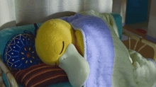 a yellow stuffed animal is sleeping on a bed