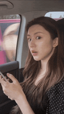 a woman is sitting in a car looking at her cell phone