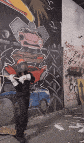 a man wearing a helmet and gloves is holding a hammer in front of a graffiti wall