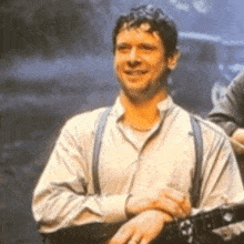 a man wearing suspenders and a white shirt is holding a guitar and smiling .