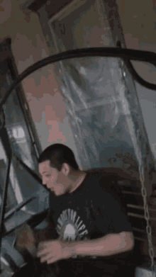 a man wearing a black shirt with a skull on it is sitting on a chair