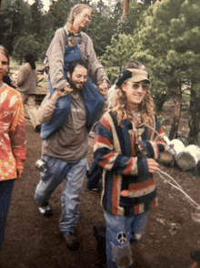 a man with a peace sign on his pants is carrying a woman on his shoulders