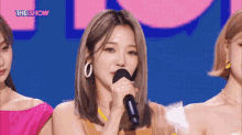 a woman holds a microphone in front of a screen that says the show on it