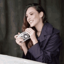 a woman is smiling while holding a camera