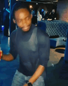 a man in a blue shirt is dancing in a room with blue couches