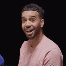a man in a pink shirt is making a funny face and smiling .