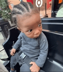 a baby is sitting in a car seat with a target sign behind him