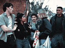 a group of people are standing in front of a brick building and one of them has a jacket with the word eagle on the front