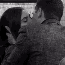 a man and a woman kissing in a black and white photo