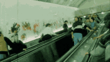 a blurred image of people riding an escalator with graffiti on the wall behind them