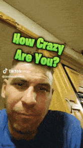 a man in a blue shirt has a sticker on his face that says " how crazy are you "