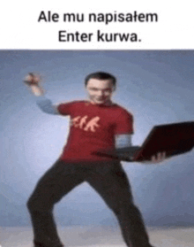a man in a red shirt is holding a laptop computer while dancing .
