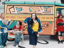 a group of women are standing in front of a hot dogs and cold drinks van