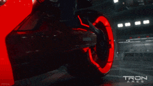 a tron ares poster with a red motorcycle in the background