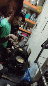 two men are cooking in a kitchen with one wearing a green shirt that says ' a ' on it