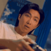 a man in a white shirt is holding a camera in his hand .