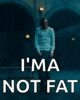 a man in a white shirt is walking down a street with the words `` i 'm not fat '' written on it .