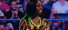 a woman with green hair is standing in a wrestling ring smiling .