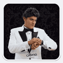 a man in a tuxedo is looking at his watch and the words casino black are on the bottom