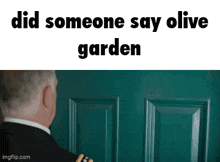 a man in a suit is standing in front of a green door and looking at it .
