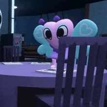 a stuffed animal with a heart on its wings sits on a table