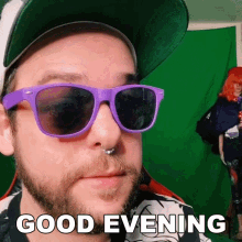 a man wearing purple sunglasses and a hat says " good evening "