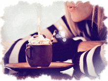 a woman blows a kiss at a cup of hot chocolate with whipped cream