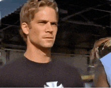 a man wearing a black shirt with a cross on it looks at the camera