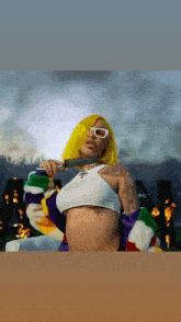 a woman with yellow hair and white sunglasses holds a knife