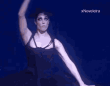 a woman in a black dress is dancing on a stage in a dark room .