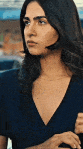 a close up of a woman 's face with a blue shirt and a gold chain around her neck