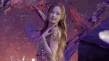 a woman in a purple dress is standing on a stage in front of a purple background .